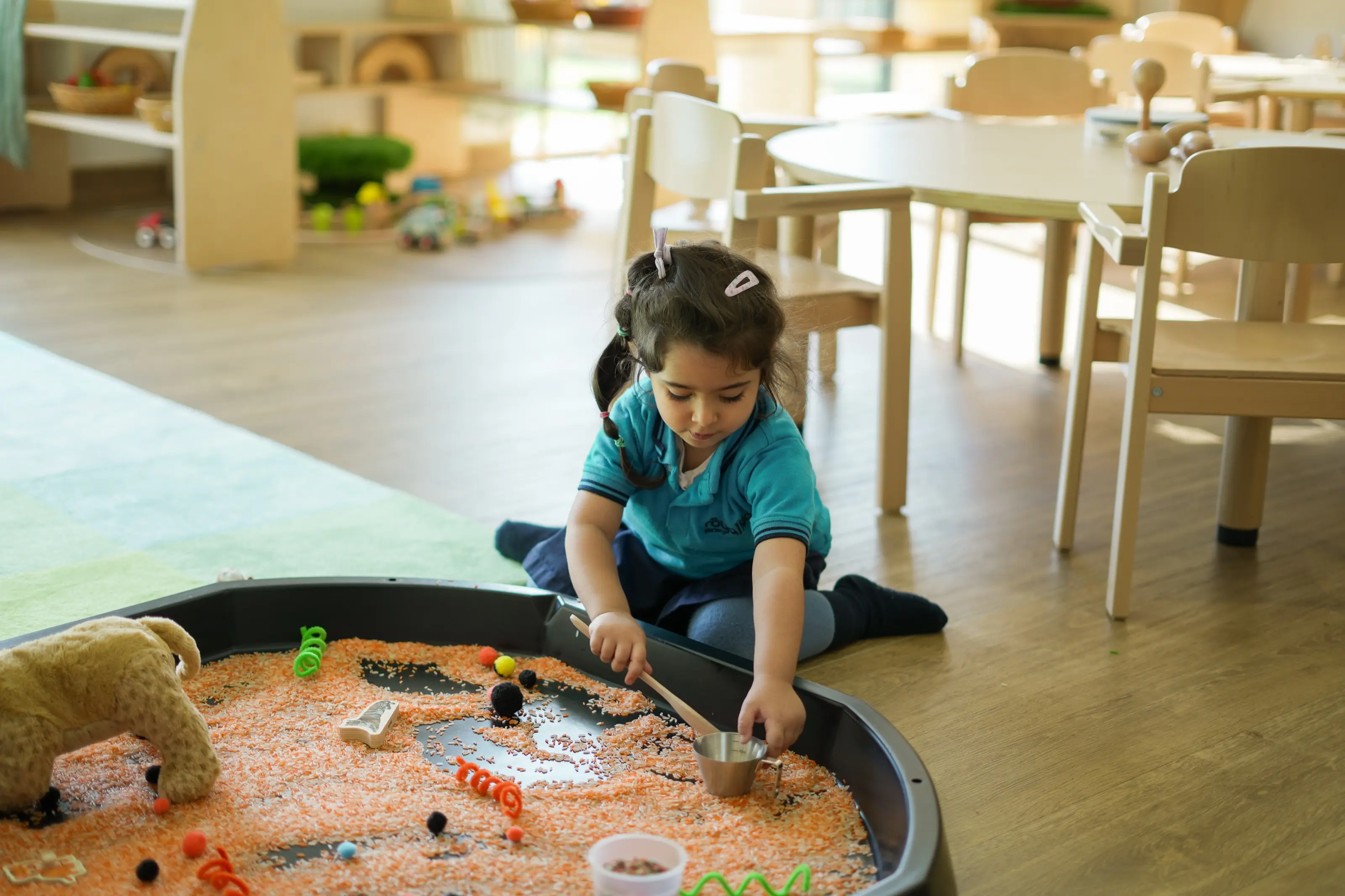 A child concentrating at a sensory tray in a sunlit Royal Kids Nursery classroom