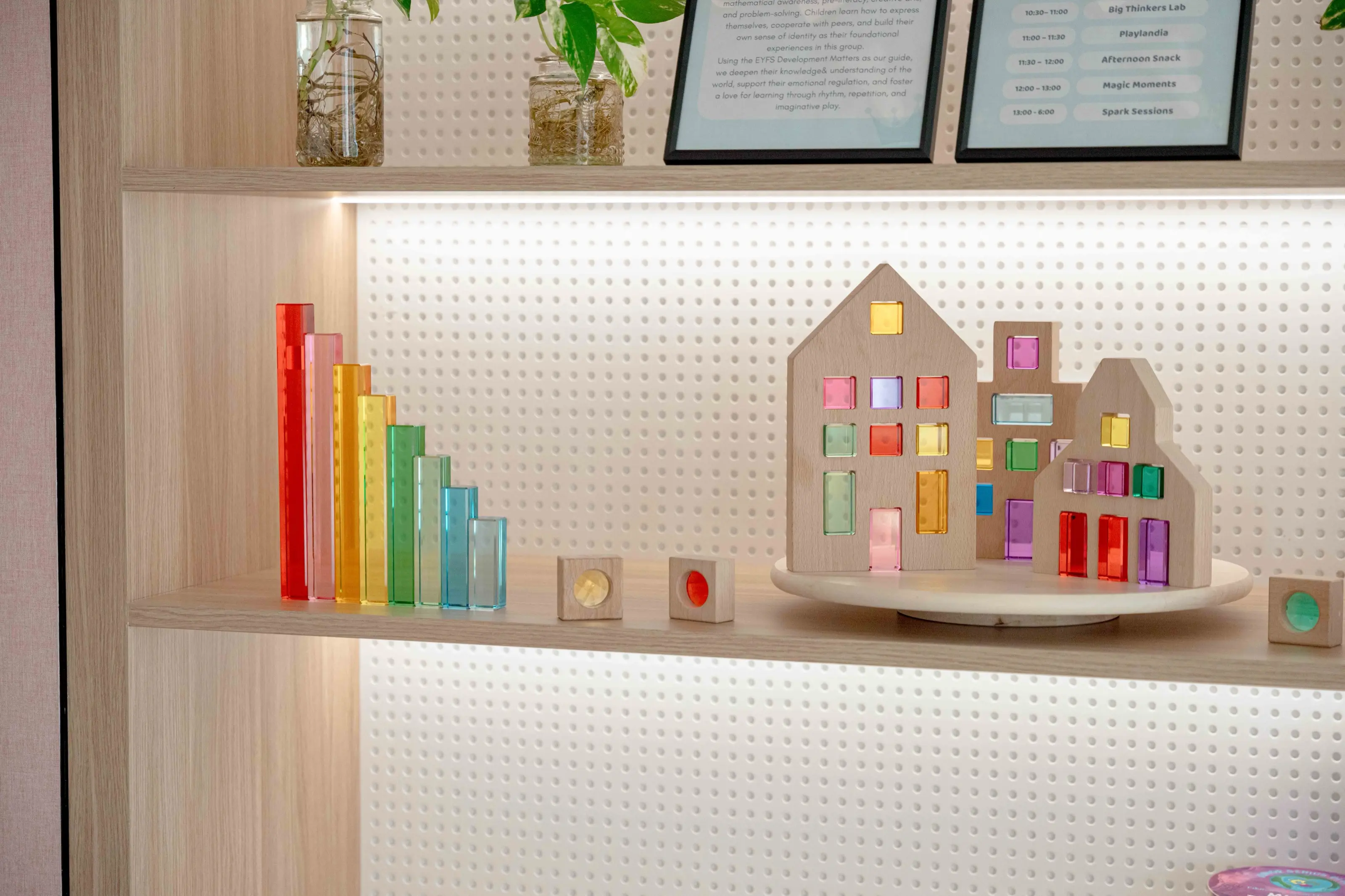 Translucent rainbow blocks and a toy house on a lit shelf in a Royal Kids Nursery classroom